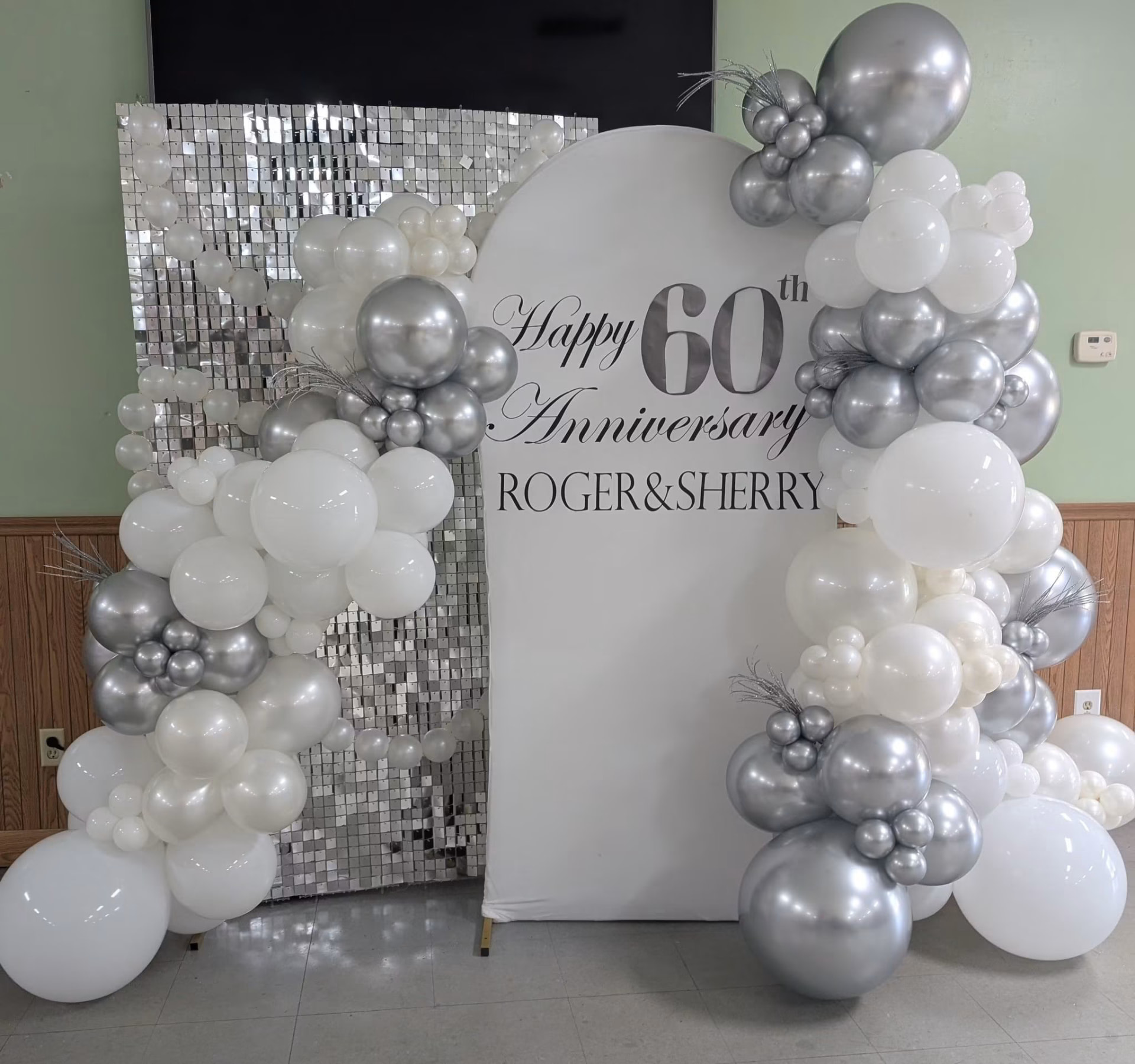 Silver and white 60th anniversary balloon arch with sequin wall